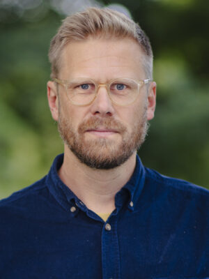 Mann med kort, blondt hår og skjegg. Foto.