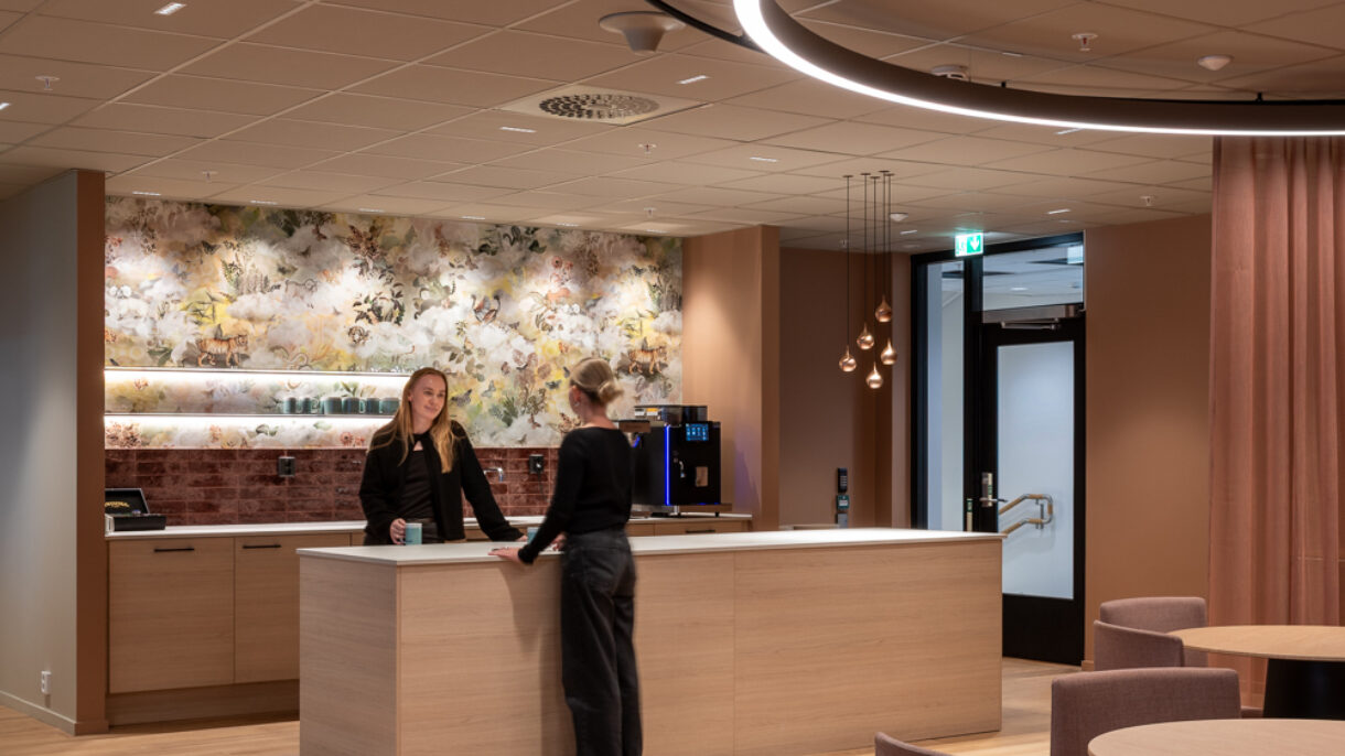 To kvinner på nyrehabilitert tekjøkken i kontorlandskap.