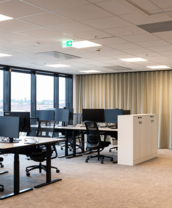 Åpent kontorlandskap med arbeidsplasser etter rehabilitering.